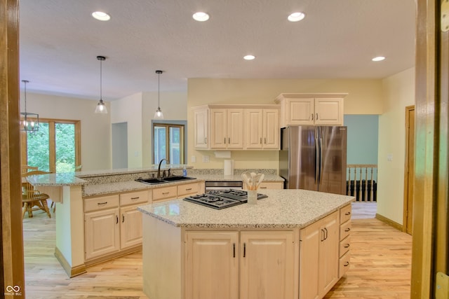 kitchen featuring sink, stainless steel appliances, a center island, light stone countertops, and decorative light fixtures