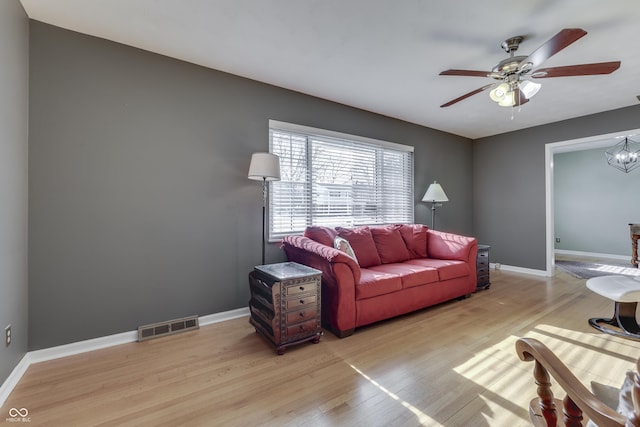 living room with ceiling fan with notable chandelier and light hardwood / wood-style flooring