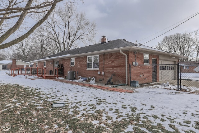 snow covered house featuring cooling unit and a wooden deck