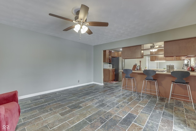 kitchen featuring kitchen peninsula, a breakfast bar, stainless steel fridge, and ceiling fan