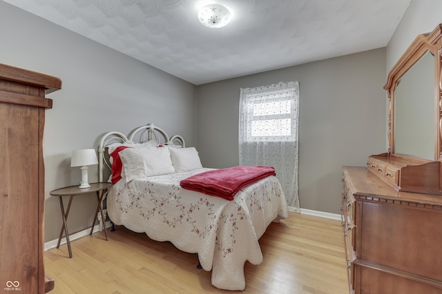 bedroom with a textured ceiling and light wood-type flooring