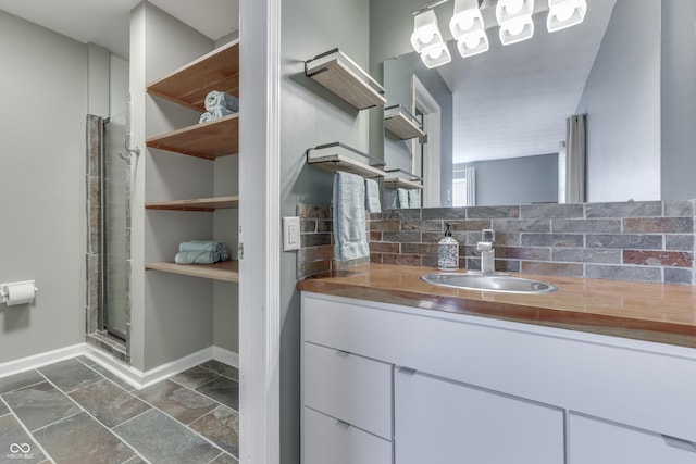 bathroom featuring a shower with door, tasteful backsplash, and vanity