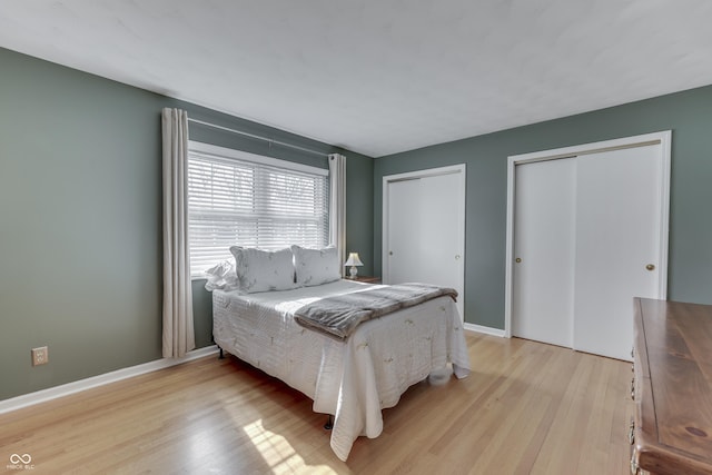 bedroom featuring multiple closets and light hardwood / wood-style flooring