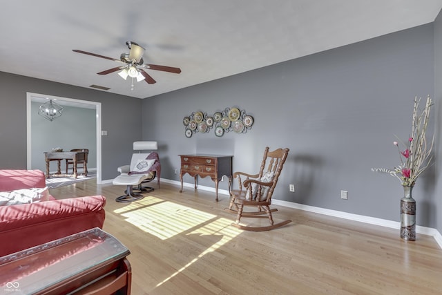 living room with ceiling fan with notable chandelier and hardwood / wood-style floors