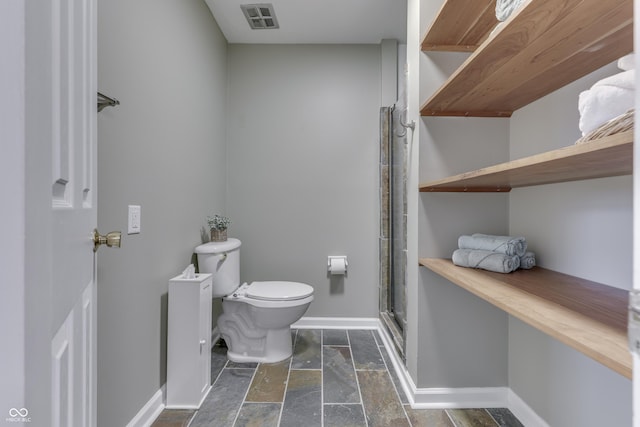 bathroom featuring toilet and a shower with shower door