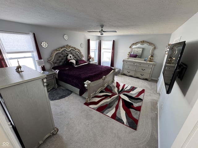 bedroom with ceiling fan, light colored carpet, and a textured ceiling