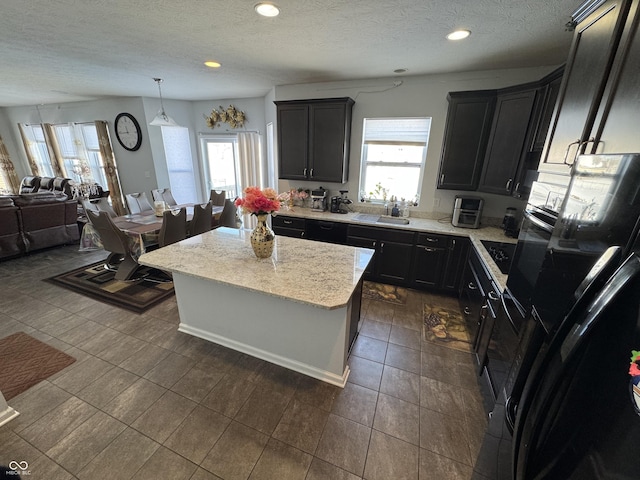 kitchen featuring black refrigerator, hanging light fixtures, a healthy amount of sunlight, and a kitchen island