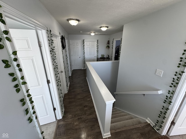 corridor with dark wood-type flooring and a textured ceiling