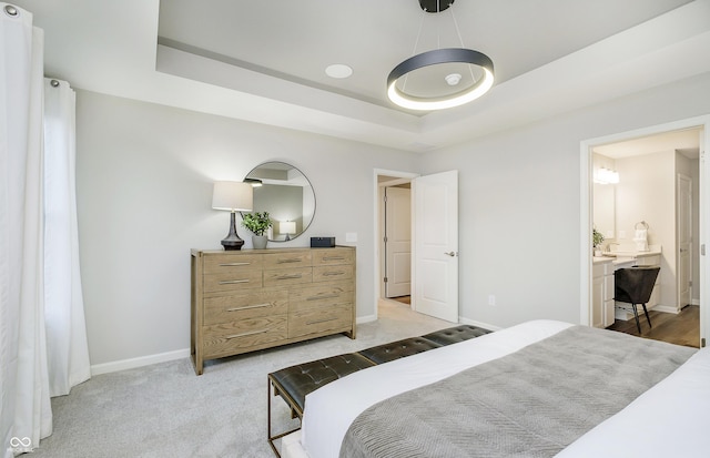 bedroom featuring a tray ceiling and light carpet