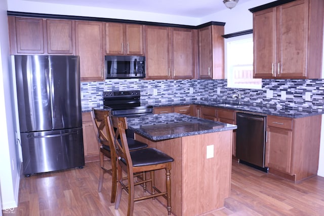 kitchen with sink, a center island, dark stone counters, and appliances with stainless steel finishes