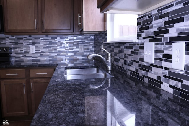 kitchen with sink, dark stone countertops, and backsplash