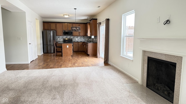 kitchen with a center island, hanging light fixtures, appliances with stainless steel finishes, a healthy amount of sunlight, and decorative backsplash