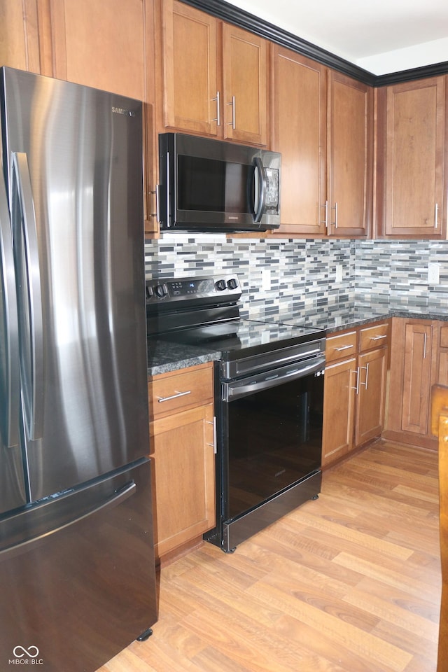 kitchen featuring dark stone countertops, black electric range oven, light hardwood / wood-style flooring, and stainless steel refrigerator