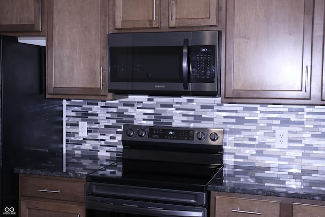 kitchen with decorative backsplash, dark stone counters, and black appliances