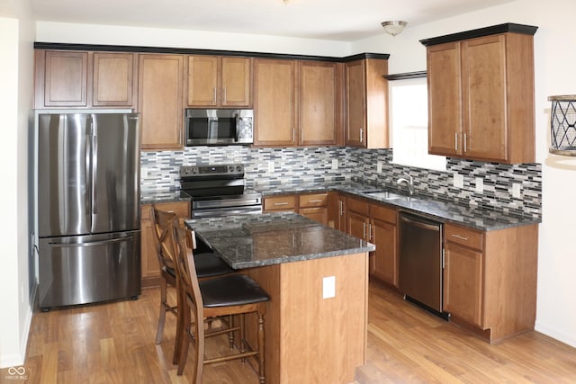 kitchen with stainless steel appliances, a kitchen island, sink, and light hardwood / wood-style flooring