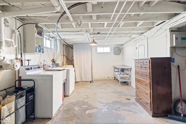 basement with electric panel and washing machine and clothes dryer