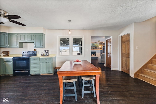 kitchen featuring ceiling fan, green cabinetry, dark wood-type flooring, black range with electric cooktop, and a textured ceiling