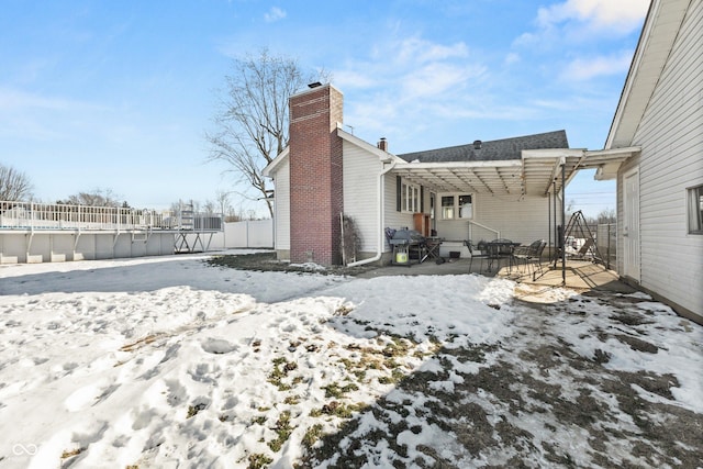 snow covered rear of property with a pergola