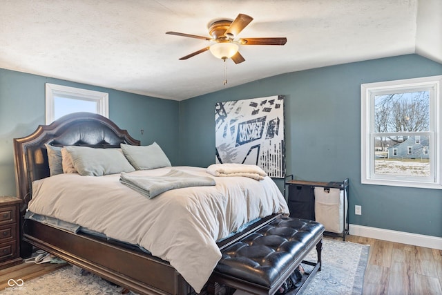 bedroom featuring ceiling fan, lofted ceiling, a textured ceiling, and light wood-type flooring