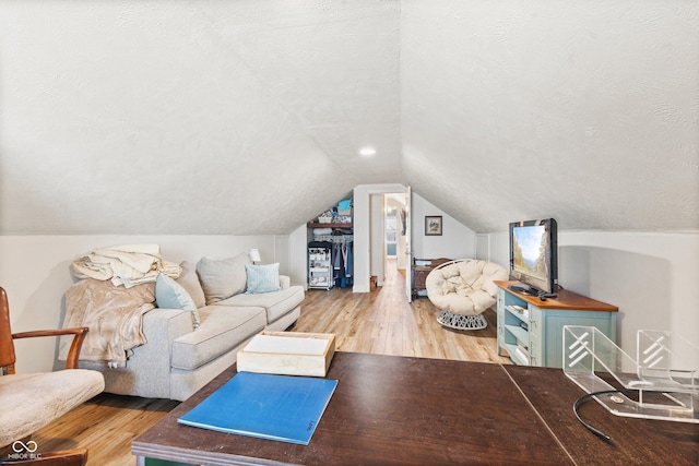 living room with vaulted ceiling, hardwood / wood-style floors, and a textured ceiling