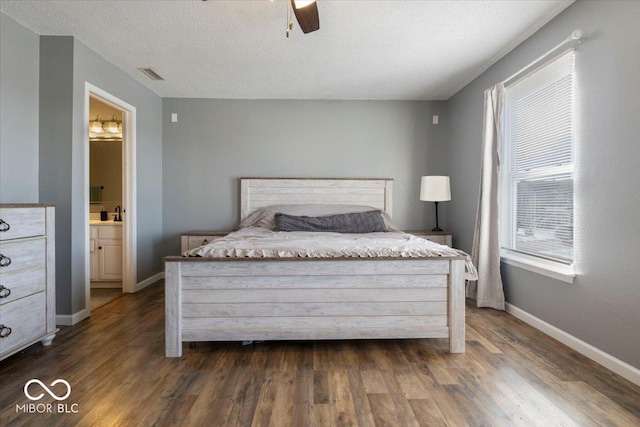 bedroom featuring ceiling fan, connected bathroom, dark hardwood / wood-style flooring, and a textured ceiling