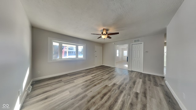 empty room featuring a textured ceiling, light hardwood / wood-style flooring, and ceiling fan