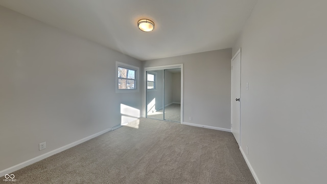 unfurnished bedroom with light colored carpet and a closet