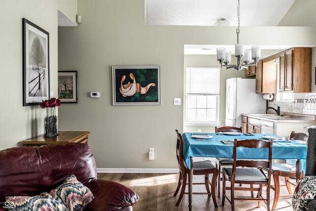 dining area with an inviting chandelier, sink, and light hardwood / wood-style floors