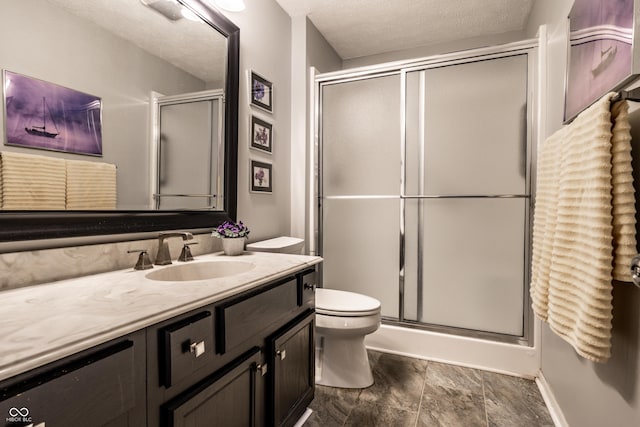 bathroom with vanity, toilet, a textured ceiling, and walk in shower