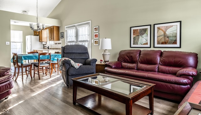 living room with an inviting chandelier, wood-type flooring, and high vaulted ceiling