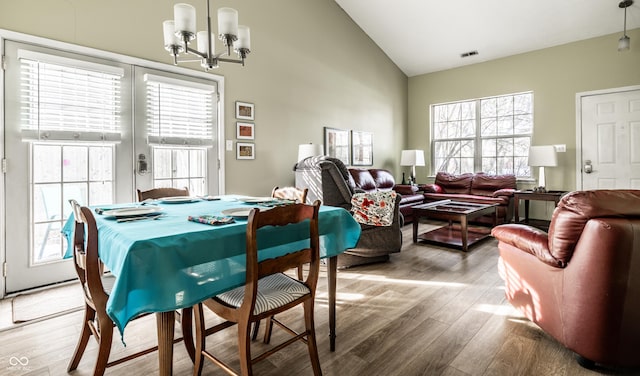 dining area with vaulted ceiling, a chandelier, and wood-type flooring