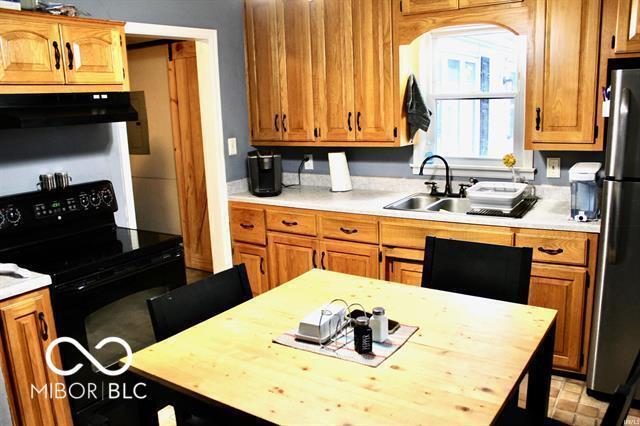 kitchen with wooden counters, black range with electric cooktop, sink, ventilation hood, and stainless steel refrigerator