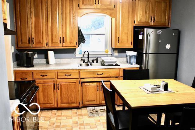 kitchen featuring sink, range, butcher block countertops, and stainless steel refrigerator