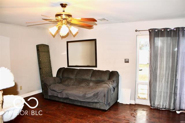 living room with dark wood-type flooring and ceiling fan