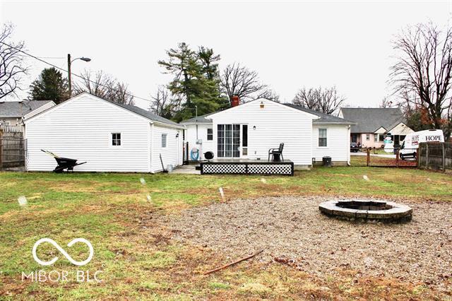 rear view of house featuring a lawn, a wooden deck, and a fire pit