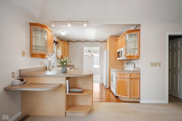 kitchen with kitchen peninsula, white appliances, a breakfast bar area, and light brown cabinetry