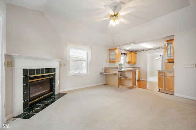 carpeted living room with ceiling fan, a tile fireplace, and lofted ceiling