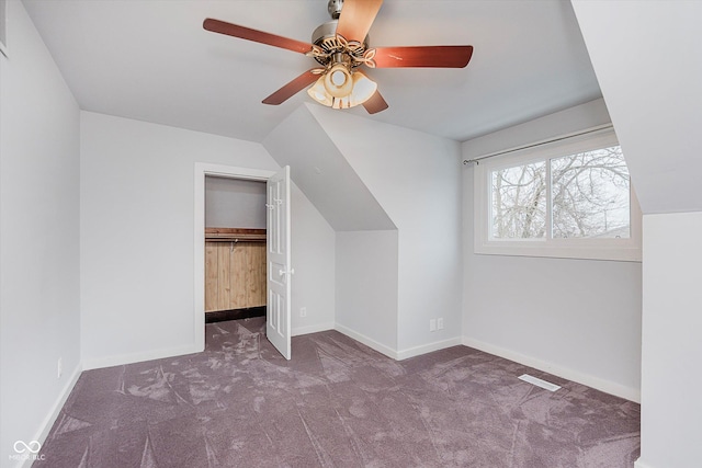 additional living space featuring lofted ceiling, ceiling fan, dark carpet, and baseboards