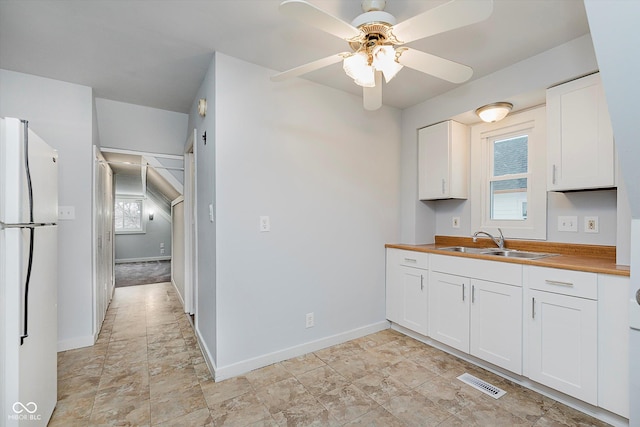 kitchen featuring a sink, visible vents, white cabinetry, wooden counters, and freestanding refrigerator