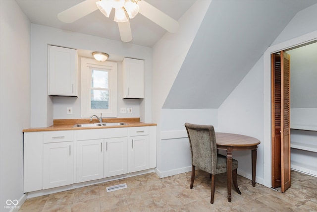 kitchen with visible vents, butcher block counters, a sink, and white cabinetry