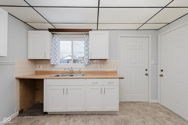 kitchen with tasteful backsplash, sink, and a paneled ceiling