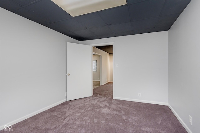 carpeted spare room featuring a drop ceiling