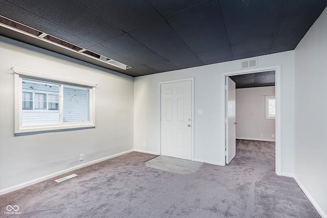 carpeted empty room with plenty of natural light and a paneled ceiling