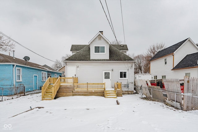 snow covered rear of property with fence and a wooden deck