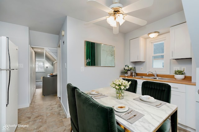 kitchen with freestanding refrigerator, white cabinetry, wooden counters, and a sink