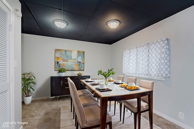 dining area with a drop ceiling and baseboards