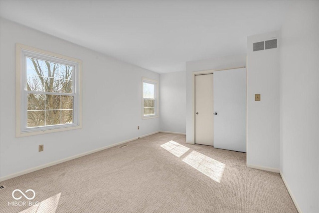 unfurnished bedroom featuring visible vents, light carpet, baseboards, and a closet