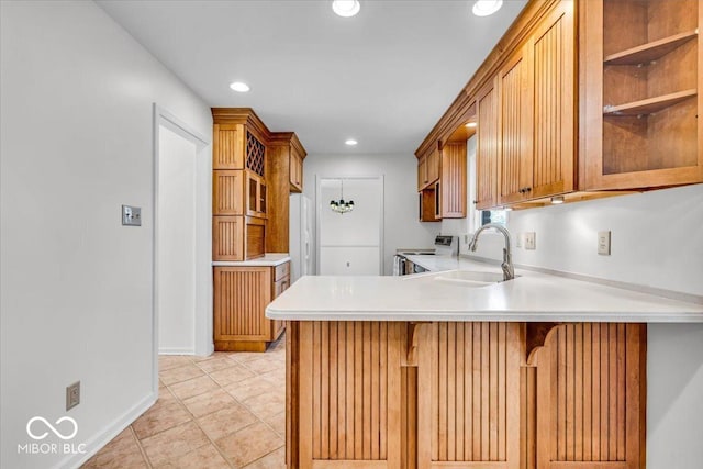 kitchen with light countertops, a kitchen breakfast bar, range with electric stovetop, a peninsula, and a sink