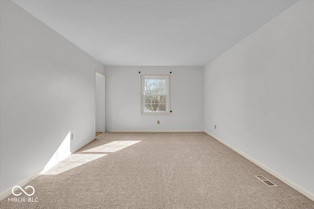 empty room featuring baseboards, visible vents, and light carpet