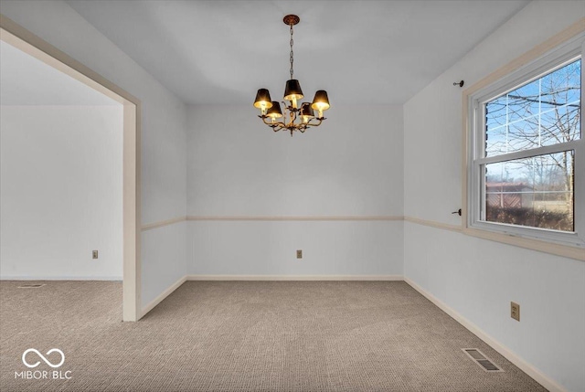 carpeted spare room featuring visible vents, baseboards, and a notable chandelier